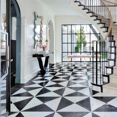 a black and white checkered floor in a house with stairs leading up to the second floor