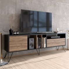 an entertainment center with a large television on it's stand in front of a concrete wall