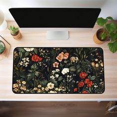 a computer desk with a flowery pattern on it and a plant next to it