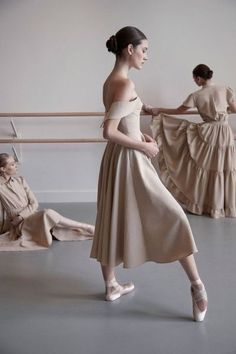 two ballerinas in beige dresses and one is sitting on the floor with her legs crossed