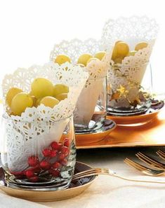 two glass vases filled with lemons and cranberries on top of a plate