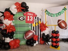 balloons and footballs are arranged in front of a backdrop for a football themed party