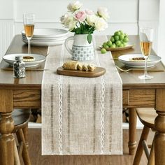 the table is set with plates, glasses and flowers in a vase on top of it