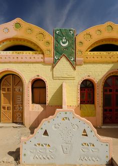 an old building that has been painted yellow and pink with ornate decorations on the front