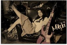 a woman laying on top of a chair next to a guitar