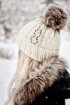 a woman wearing a white hat with a fur pom