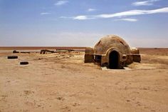 an old building sitting in the middle of a desert with no people around it and blue skies above