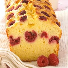 a loaf of raspberry bread sitting on top of a white towel next to some raspberries