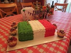 there is a cake made to look like the flag of italy on a table with cupcakes