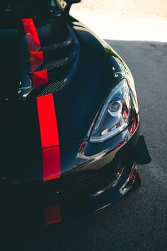 the front end of a black sports car with red stripes