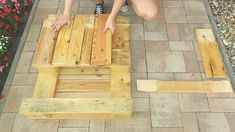 a woman kneeling down on top of a wooden bench made out of pallet wood