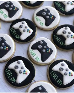 decorated cookies with video game controllers are on a white tablecloth and have words written on them