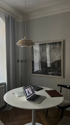 a laptop computer sitting on top of a white table in front of a large window