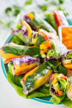 a plate filled with lettuce, carrots and other vegetables next to dipping sauce