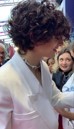 a woman in a white suit signing autographs for people