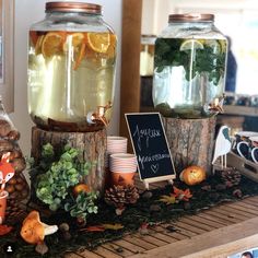 three jars filled with liquid and plants on top of a wooden table next to a chalkboard