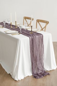 the table is set with two chairs and a white table cloth draped over it, along with candles