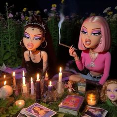 two dolls sitting on the ground with candles in front of them