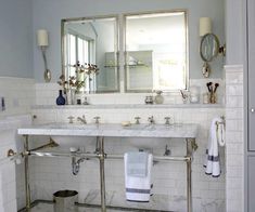 a bathroom with two sinks, mirrors and towels hanging on the rack in front of it