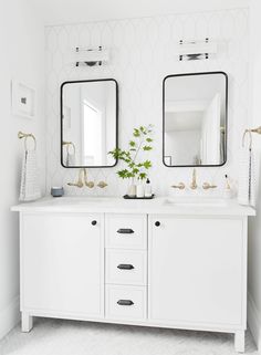 two white bathroom sinks with gold faucets and mirrors on the wall above them