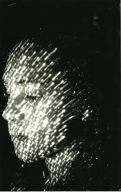 a black and white photo of a woman's face with light shining through her hair