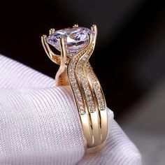 a close up of a gold ring with diamonds on it's side and an oval cut diamond in the center