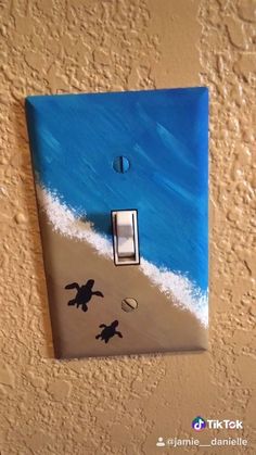 a light switch cover with sea turtles on the beach painted on it's side