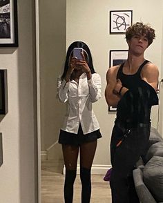 a man taking a selfie in front of a mirror while standing next to a woman