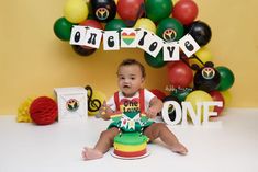 a baby sitting in front of a cake with the words one love spelled on it