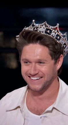 a smiling man wearing a crown on top of his head