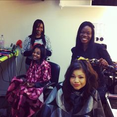 three women are getting their hair done in a salon room with one woman sitting on the chair and another standing up