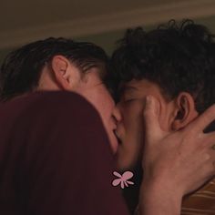 two young men kissing each other in front of a window with the light on and one man's face partially obscured by his hands