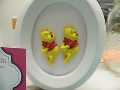 two winnie the pooh figurines sitting on top of a white plate next to a card