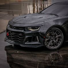 the chevrolet camaro zr1 is parked in front of a building on a rainy day