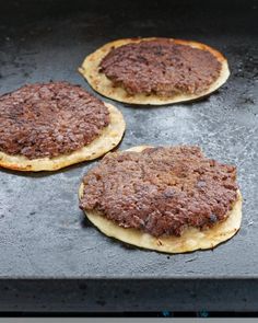 three hamburger patties sitting on top of a baking sheet