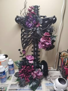 there is a skeleton made out of flowers on top of a table with paint and pencils