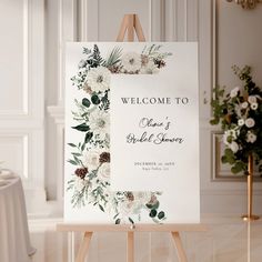 an easel with a welcome sign on it in front of a table and flowers