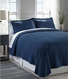 a bed with blue bedspread and white pillows