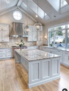 a large kitchen with white cabinets and marble counter tops, an island in the middle