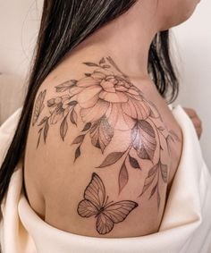 a woman's shoulder with a flower and butterfly tattoo on her left side breast