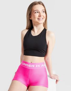 a woman in pink shorts and a black tank top is posing for the camera with her hands on her hips