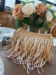 a vase filled with flowers sitting on top of a table next to a straw bag