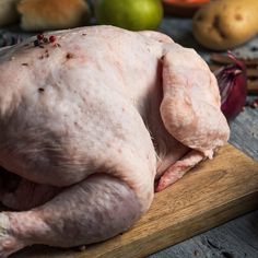 a raw chicken sitting on top of a wooden cutting board