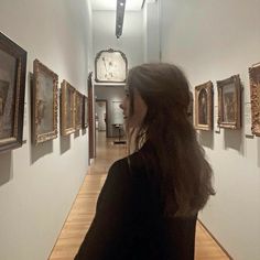 a woman is looking at paintings on the wall