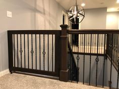 a staircase with wrought iron railing and chandelier