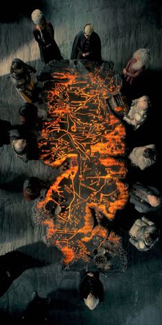 a group of people sitting around a table covered in orange and black fire with faces drawn on it