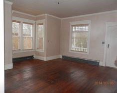 an empty living room with hard wood floors and white trim on the windows in the corner