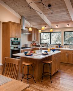 a kitchen with wooden floors and white counter tops next to an island in the middle