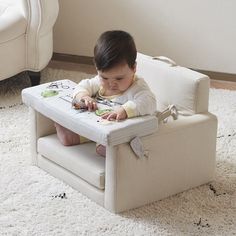 a baby sitting in a chair on the floor