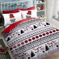 a bed covered in red and white sheets with christmas decorations on it, sitting next to a window